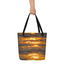 Load image into Gallery viewer, A tote bag seen from the front carried by a female hand. An orange reflection printed on a large bag.