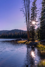 Load image into Gallery viewer, A limited edition vertical image of a twilight in Crystal Lake, Utah. The sun shines behind the foliage of a pine tree.