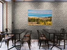 Load image into Gallery viewer, "'Enchanting Hues' 40" x 60" - Adorning a dark cream brick wall in a rustic restaurant with glass tables and dark metal chairs, adding life and vibrancy to the space."