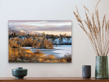 Load image into Gallery viewer, •	"’The Best Winter Colors’ 16" x 24" - Enhancing a white wall, above a wooden table with small potted plant, showcasing the relationship between size and surroundings."