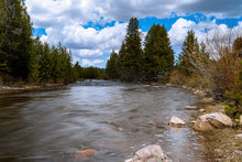Load image into Gallery viewer, Long-exposure photo of the Bear River in Kamas, Utah, with flowing spring water, pine trees, and a cloudy sky.
