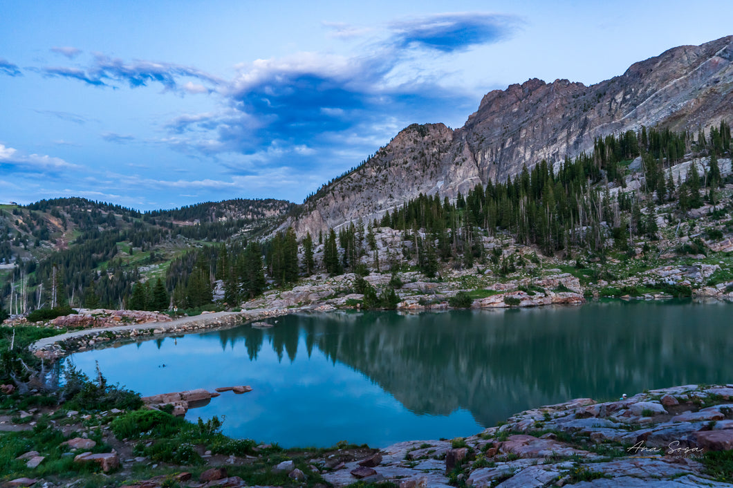 A photography of Cecret Lake sunset. The sky and mountains reflecting on the water showing cool temperture