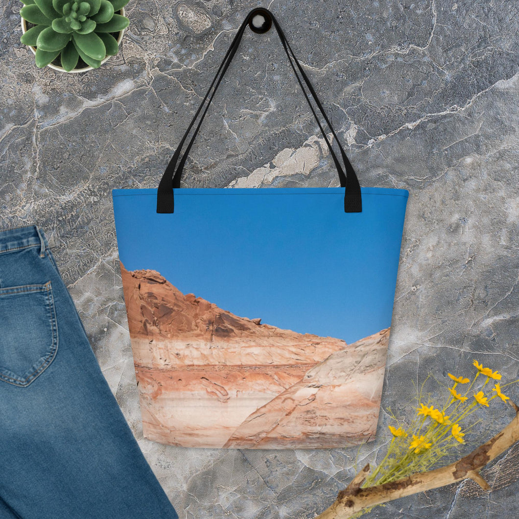 A tote bag, seen from front side, completely printed, blue sky and rock formations with black hanger