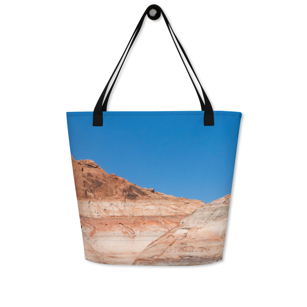 A modern tote bag, seen from one side. Printed completely, blue sky and rock formations.