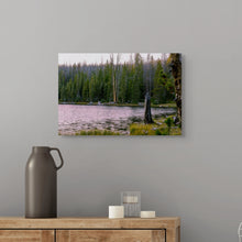 Load image into Gallery viewer, A 16x24&quot; image showing a pink sunset reflected over Crystal Lake - Utah, downloadable with user license. A pine forest in the background of the photo, displayed on a gray wall above a counter
