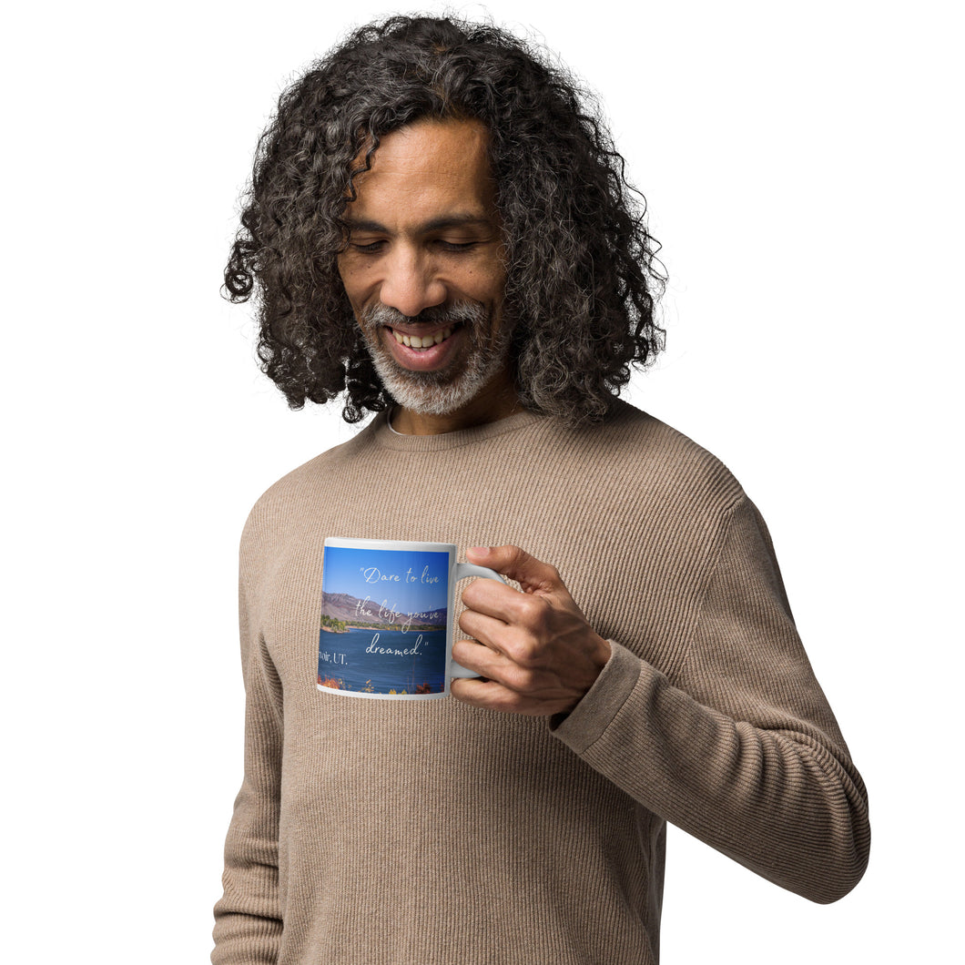 A man with a white glossy 20 oz mug with Pineview Reservoir image, handle on right.