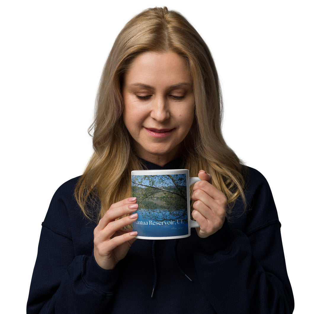 A woman with a white glossy 20 oz mug with Mantua Reservoir image. Handle on right