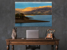 Load image into Gallery viewer, &#39;Sunset Over The Mountains&#39; - 40&quot;x60&quot; on a dark grey wall in an elegant room with a small Victorian-style desk, an antique phone, and a white laptop.
